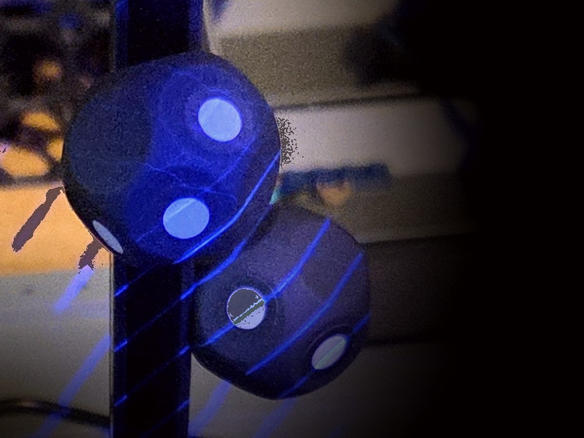 Coded marker reference spheres on a post beside the scanning turntable, lit by blue laser lines