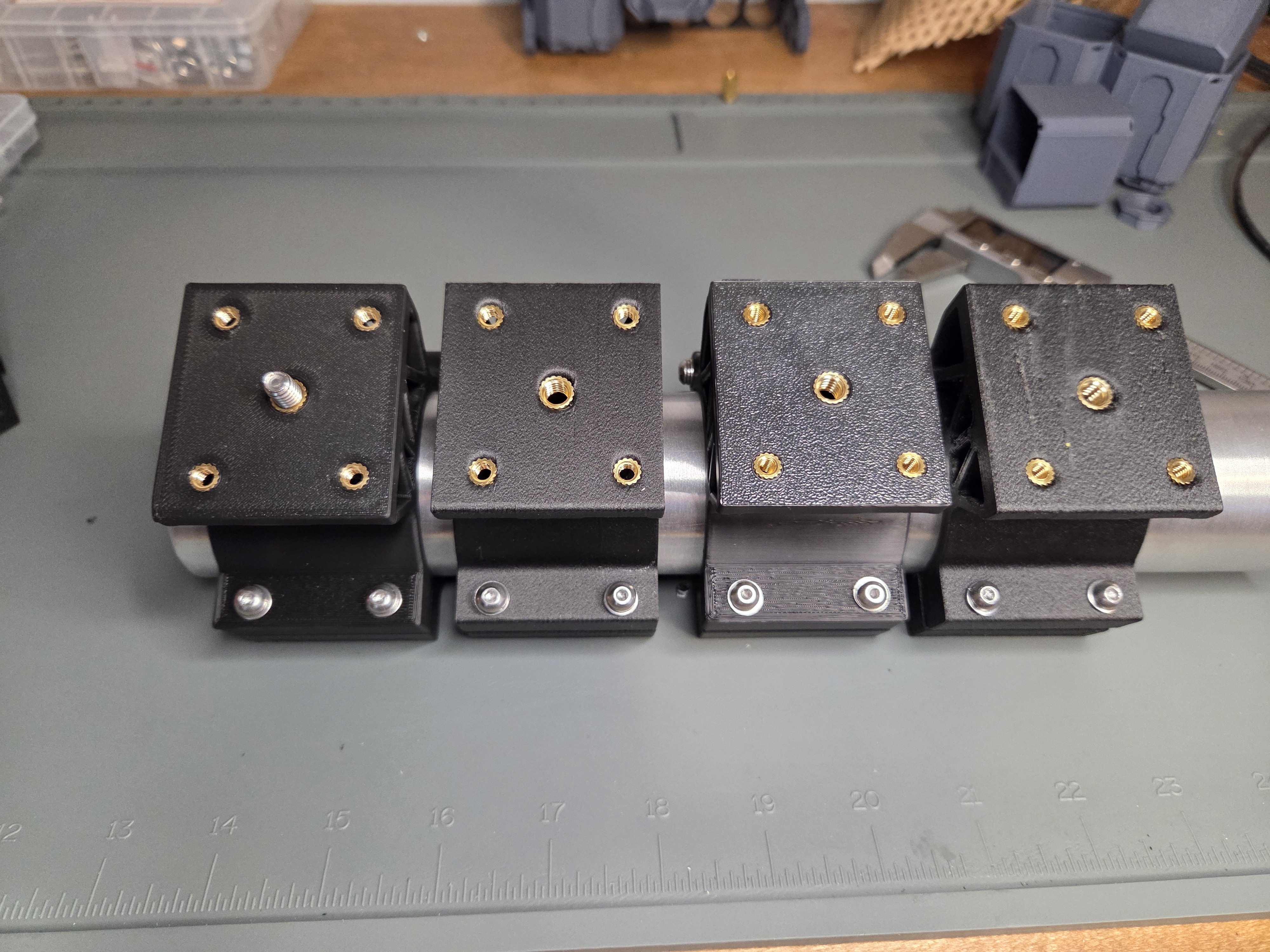 Four universal clamp mounts arranged on a polished aluminum shaft showing small-batch consistency