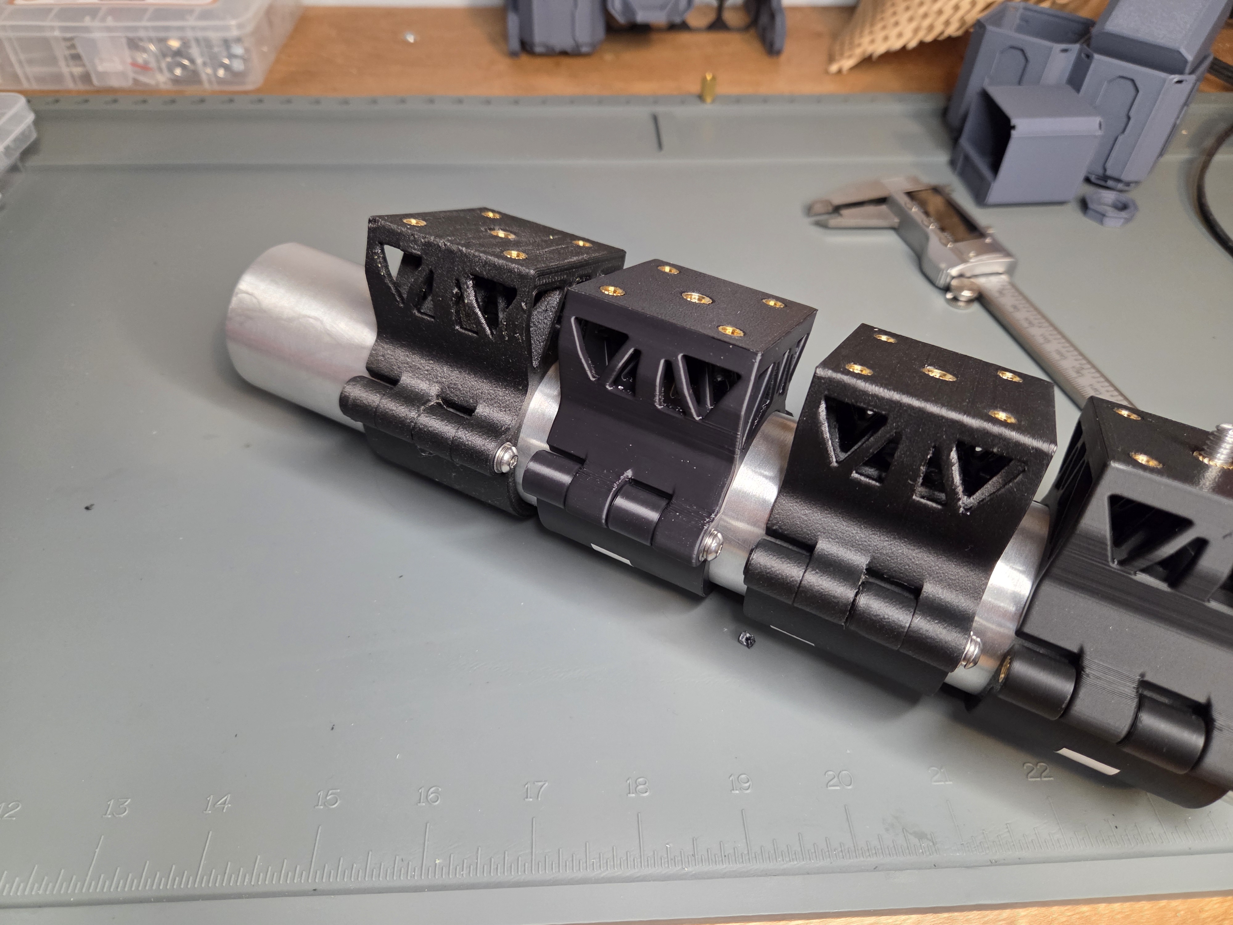Side profile of universal clamp assembly showing topology-optimized triangular cutouts and hinged clamping mechanism